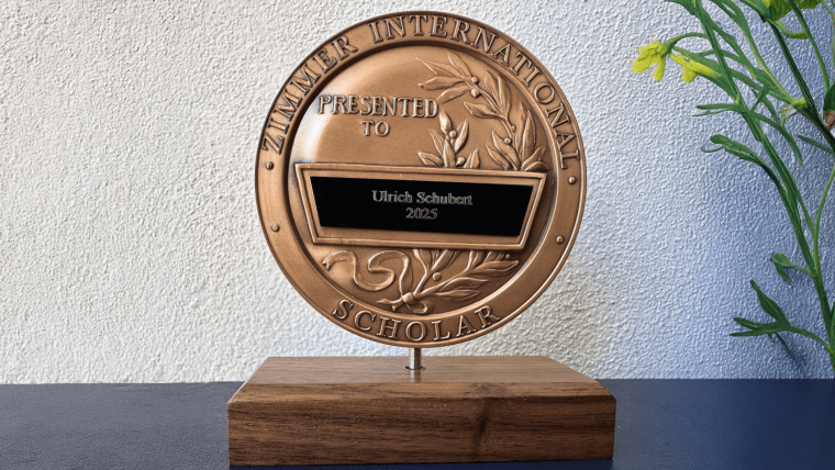 Bronze Zimmer International Scholar Award plaque presented to Ulrich Schubert in 2025, mounted on a wooden base.