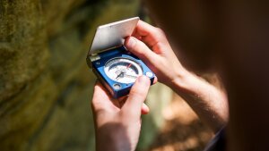 A person holds a compass in his hands.
