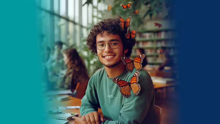Ein junger Mann sitzt in einer Bibliothek am Tisch, um ihn Schmetterlinge