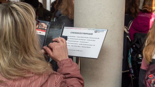 Eine Besucherin fotografiert das Eingangsschild zur Thüringer Chemieolympiade 2024 an der Uni Jena