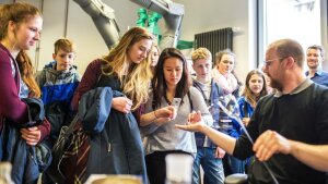 School students watch an employee in the glassblowing office at the University of Jena at work.