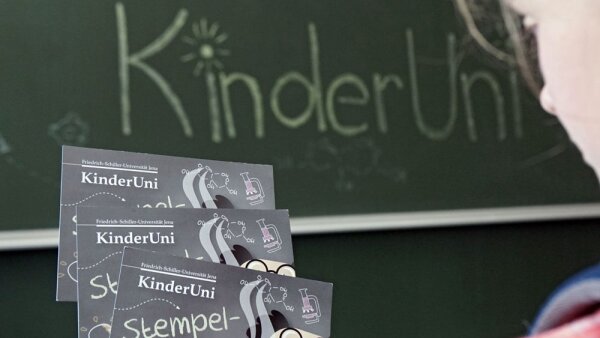 Ein Kind hält Stempelkarten für die KinderUni an der Universität Jena in der Hand.