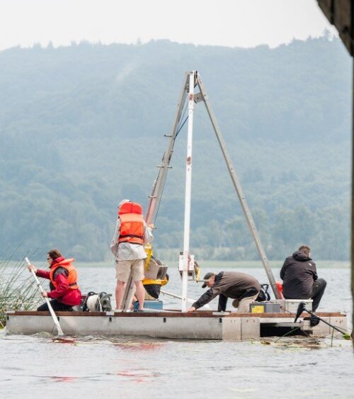 Fünf Wissenschaftler stehen auf einer Bohrplattform auf einem See.